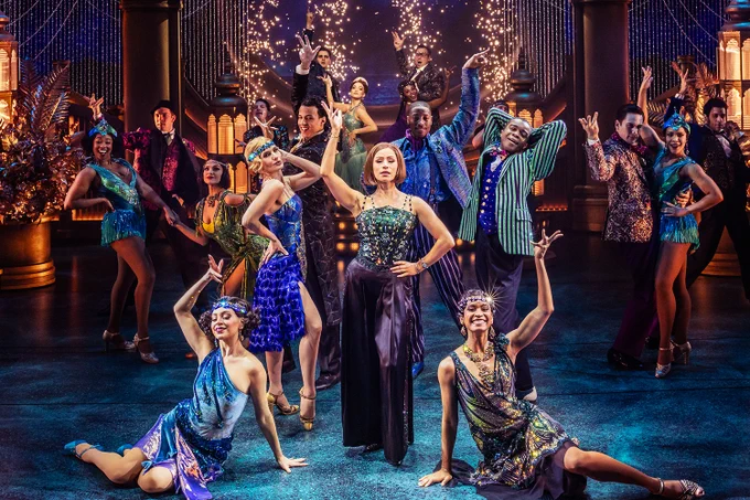 A photo showing an elaborate scene with a group of performers dancing in vintage outfits 