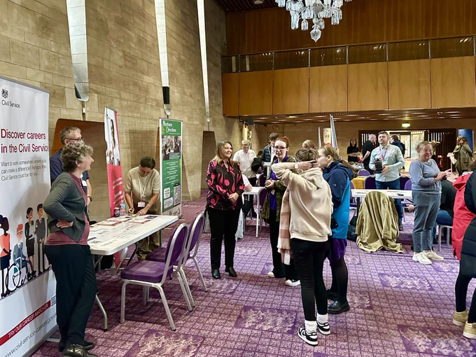 Employers and partners from around the city standing at tables with attendees present in the Banqueting Hall, Civic Centre.