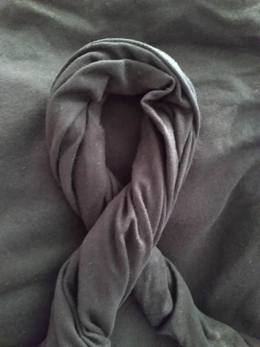 black fabric twisted into a one-loop ribbon bow against more black fabric 