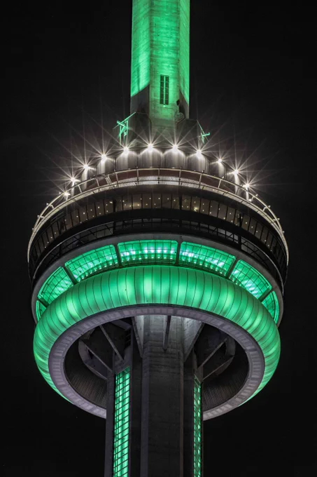 Closeup of the CN Tower at night lit green / Gros plan de la Tour CN illuminée en vert la nuit.