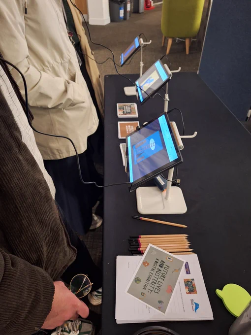 Three people stood in a row listening to the exhibition on tablets.