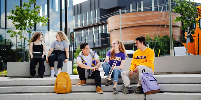 Students sit at the Music Faculty entrance of the Waterloo campus.