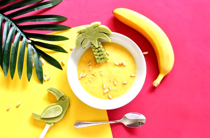 Image shows a colourful bowl of food and a banana, prepared for children