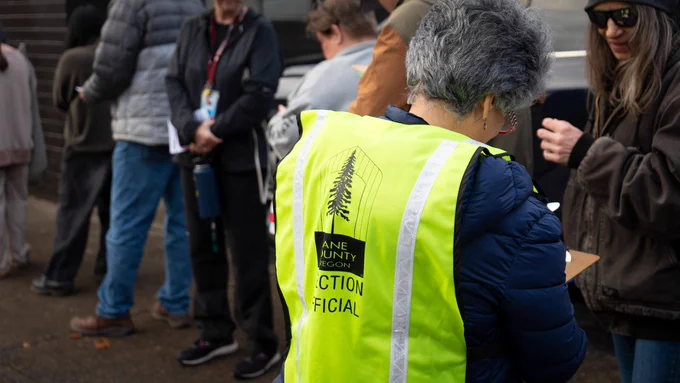 An election worker assists people in line outside the Elections Office on Election Day.