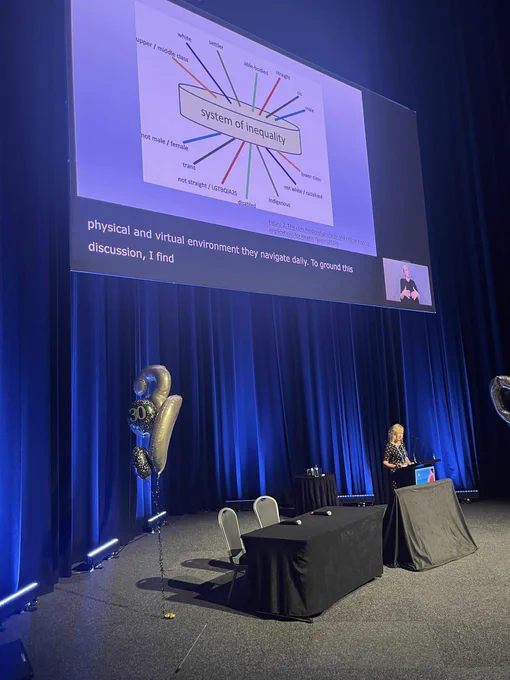 A person at a lectern with a slide on screen