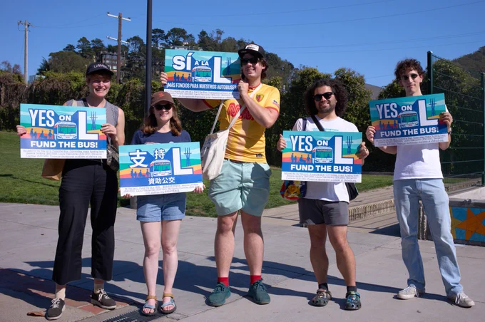 5 volunteers holding Fund the Bus signs