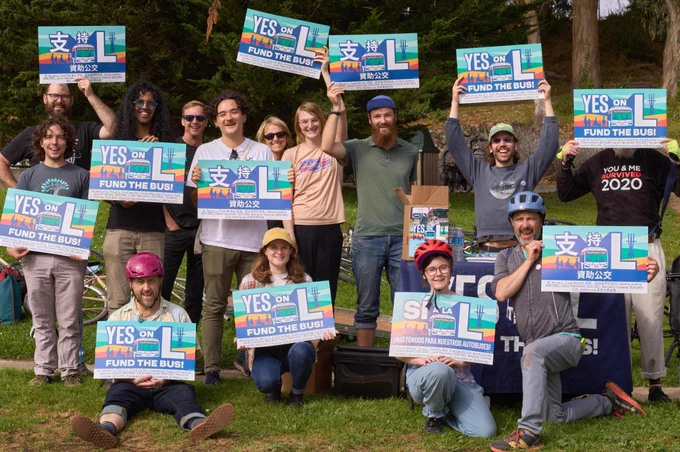 14 volunteers holding Yes on L signs