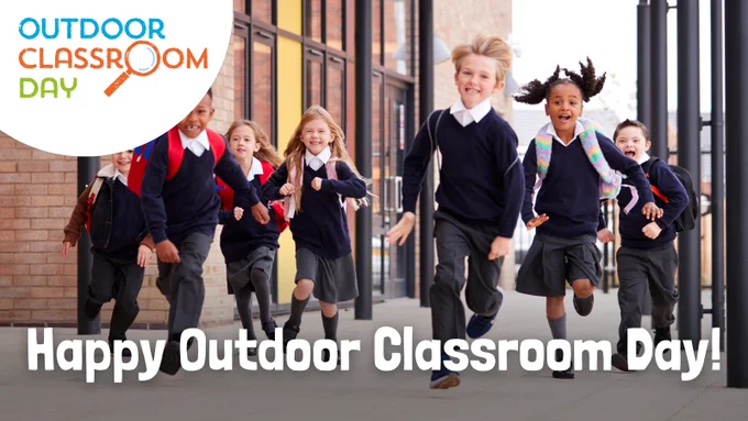 A graphic featuring an image of primary school children in school uniform, laughing as they run across the school grounds. The words 'Happy Outdoor Classroom Day!' are written in white along the bottom of the image, and the Outdoor Classroom Day logo is overlaid in the top left corner.