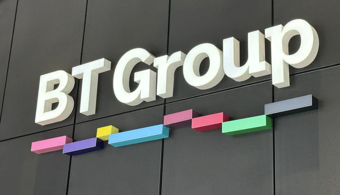 White BT Group logo mounted on a dark wall, underlined by our coloured pixels.