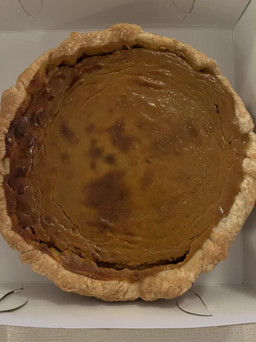 a whole pumpkin pie with a golden crust, in the center is a rich custard the color of bronze with delicate spices