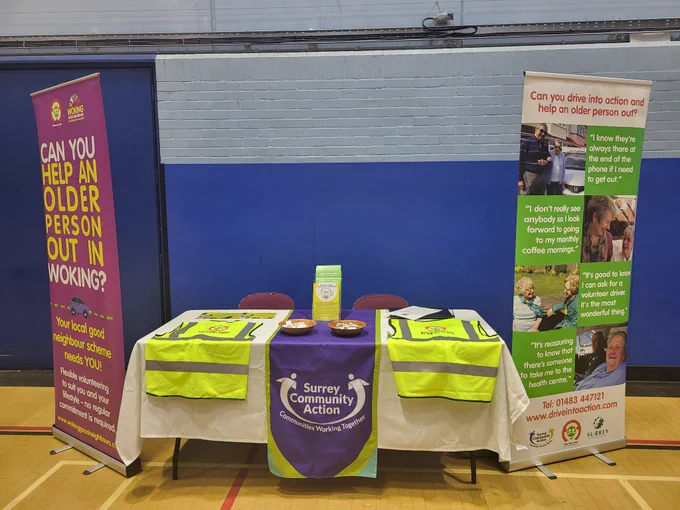 Two pop up banners stand either side of a table with high visibility vests on as well as leaflets and baskets of trolley coin key rings
