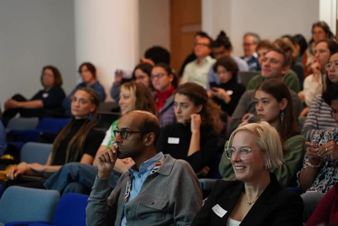Delan Devakumar and Pia Hardelid observing presentations with audience behind them