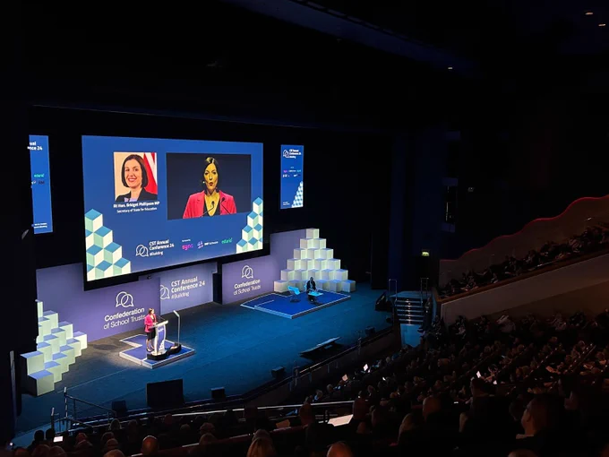 Bridget Phillipson, Secretary of State for Education, addresses CST Conference from a podium in a conference hall.