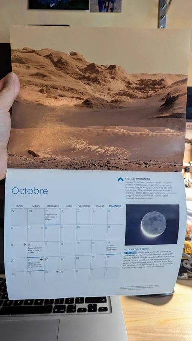 La double page du mois d'octobre du calendrier 2025 de Ciel&Espace avec une mosaïque d'images prises par le rover Curiosity. Cette image montre les yardangs du Mt Sharp, des structures creusées par l'érosion éolienne. Des dunes sombres couvrent le bas de l'image.