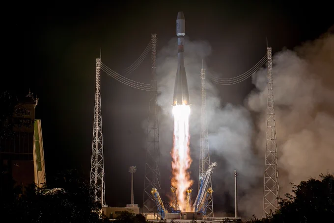 The launch of the Metop-C satellite into the night sky. The flames from the rocket's engines light up the launch pad as it lifts of.