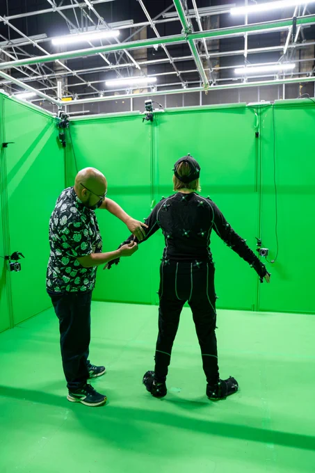 volumetric capture in a studio. two people standing in front of a green screen