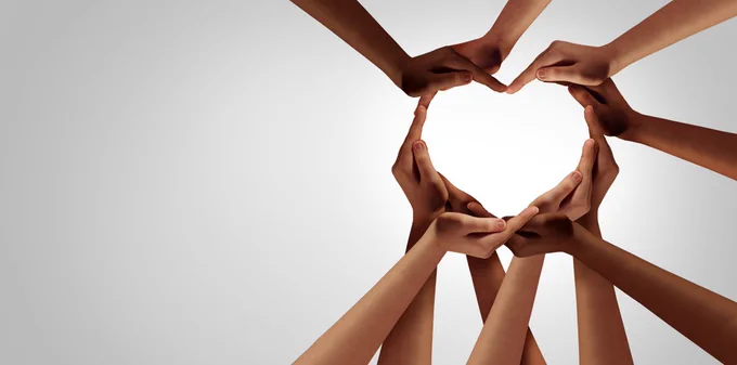 Stock image of a circle of hands - forming a love heart shape. 