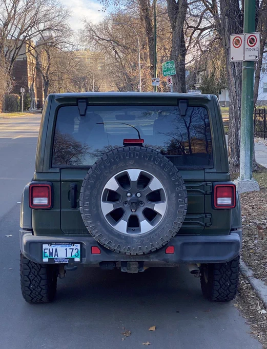 Green SUV parked in a no-stopping 7:00 to 9:00 zone.  Bike route sign above.