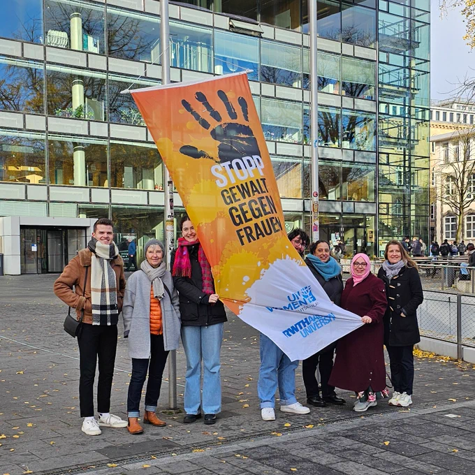 Personen vor einer orangefarbenen Flagge