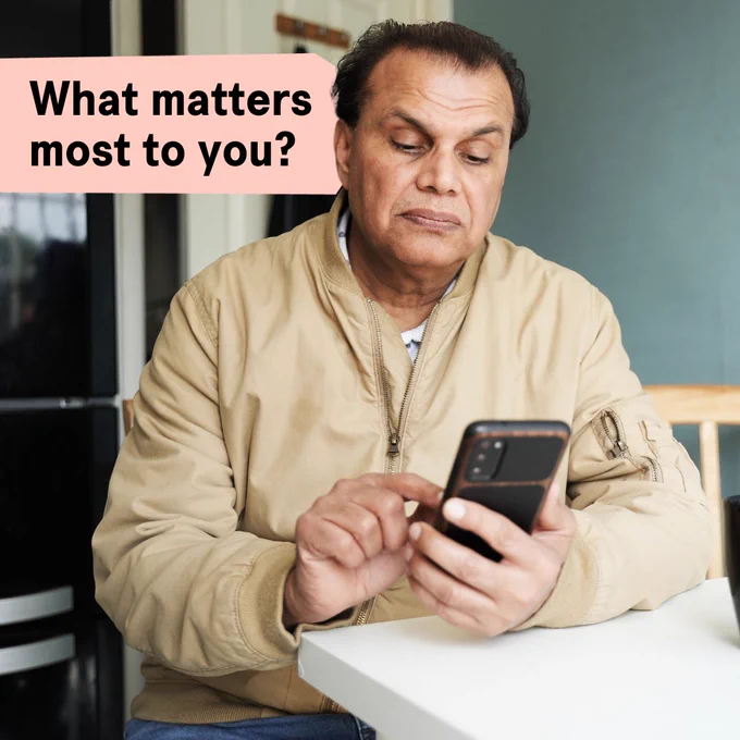 Person sitting at a table looking at a smartphone with the text 'What matters most to you?' displayed above.
