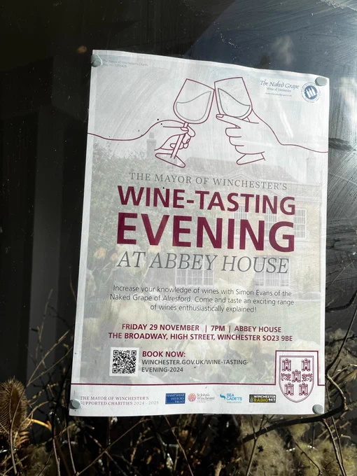 wine-tasting poster, with two glasses coming together in a 'cheers', in a shop window 