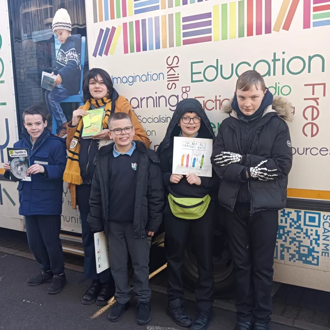Children posing with books outside the mobile library