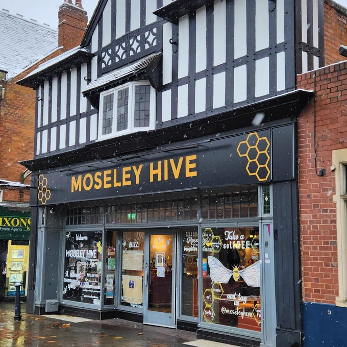 The Moseley Hive community hub in Birmingham, viewed from the street. Flakes of snow fall onto the wet pavement.