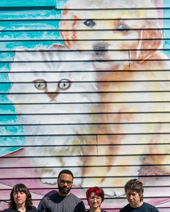 photo of Bad Moves standing in front of a mural of a dog and a cat where we're cropped pretty low in the frame and the mural takes up the most space