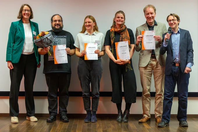 Direktorin Prof. Ulrike Cress mit Gewinner Dr. Tjark Müller mit Blumenstrauß,  Dr. Helen Fischer, Reena Pauly,  Dr. Jürgen Buder, und Moderator  Dr. Danny Flemming