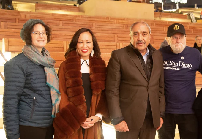 Left to right: Elizabeth Simmons, Mai Nguyen, Pradeep Khosla, and Don Norman, dressed in formal winter clothes, pose in front of lighted benches at the Epstein Family Amphitheater.
