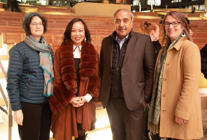 Left to right: Elizabeth Simmons, Mai Nguyen, Pradeep Khosla, and Corinne Peek-Asa, dressed in formal winter clothes, pose in front of lighted benches at the Epstein Family Amphitheater.