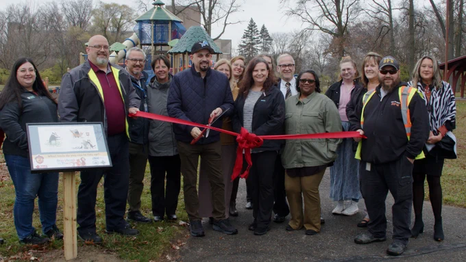 Officials representing the City of Wayne, Wayne RESA, and the Wayne Public Library cut the ribbon on the new storybook path at Attwood Park.