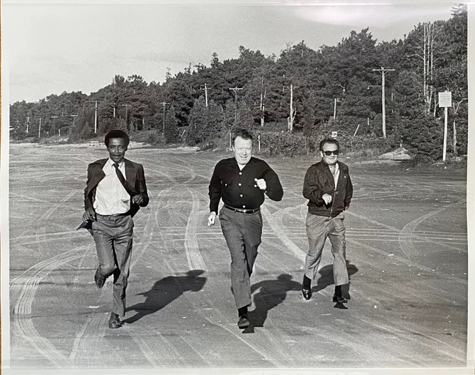Three men running together, with UAW President Walter Reuther in the middle. 