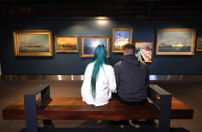 Couple sitting in front of maritime paintings