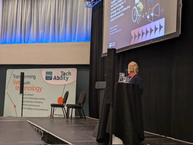 Jane Seale standing on the stage at the TechAbility conference. 