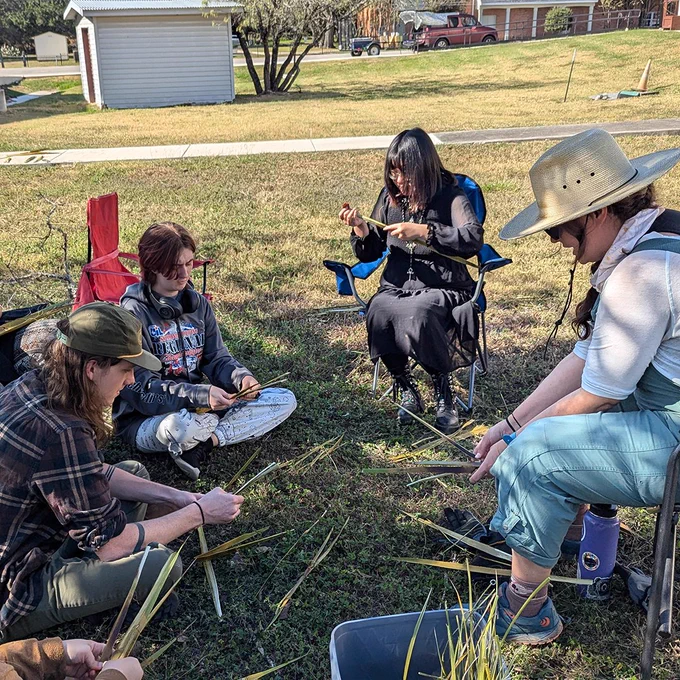 Some of the Archaeology Club members sitting outside of the Archaeology lab demonstrating and learning making sandals.