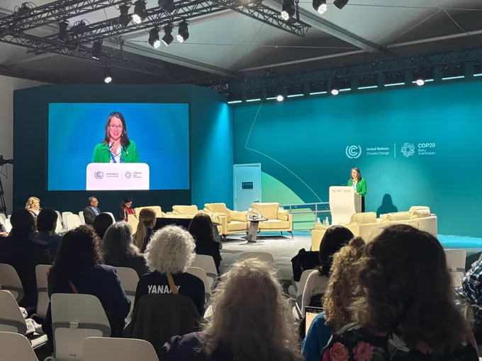 Canada’s Ambassador for Climate Change, Catherine Stewart stands behind a podium to deliver a speech to an audience at the COP29 conference.