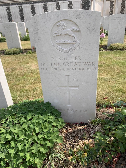 The white gravestone of a soldier stands in a graveyard