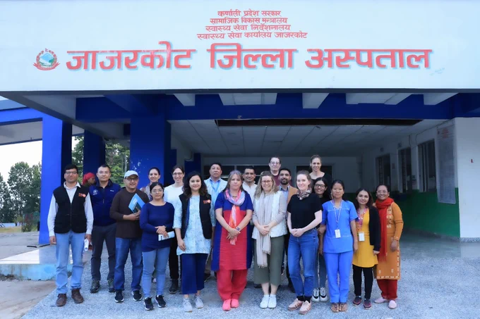 A group of people standing in two rows in front of Jajarkot District Hospital. 