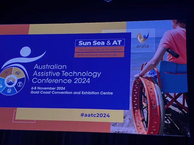 Sign of the Australia Assistive Technology Conference 2024 also depicting a person in a wheelchair on the beach.