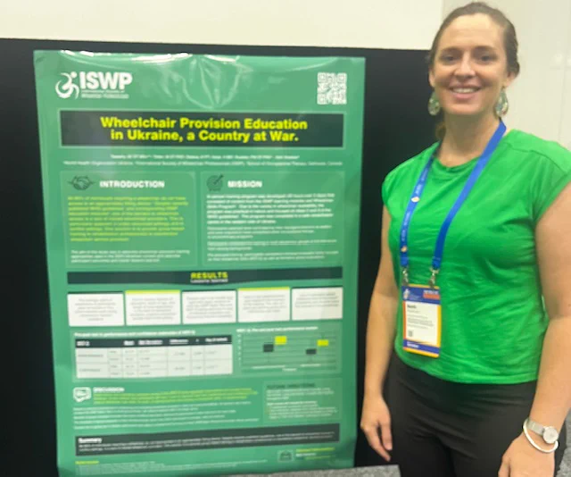 Image of Beth Sheehan standing next to the ISWP poster presentation of 'Wheelchair Provision Education in Ukraine, a Country at War'.