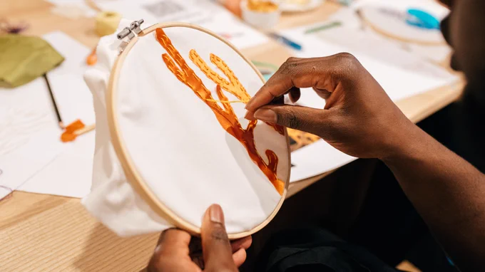 A person embroidering a piece of cloth.