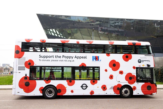Side on shot of a Transport UK London Bus with a Poppy Appeal wrap around it.