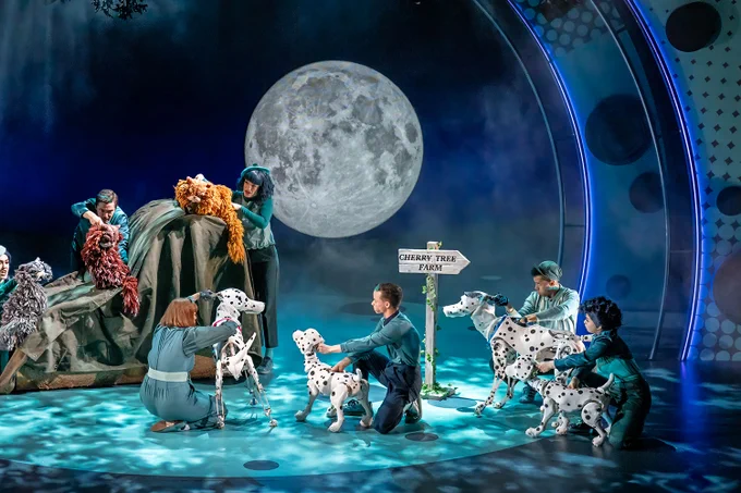 A photo showing a scene involving a group of puppet dogs being controlled on a blue-lit stage 