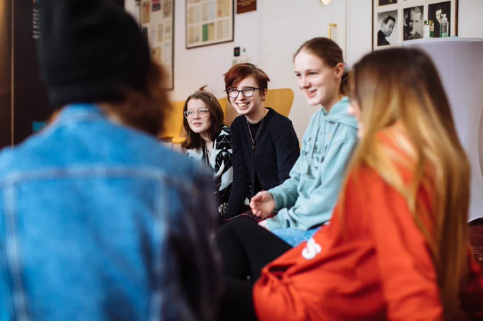 A group of young people sit and smile together.