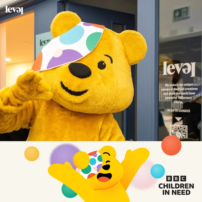A life size Pudsey Bear inside the LEVEL Centre building. Pudsey waves at the camera. They stand next to a door with the LEVEL logo on the glass insert. At the bottom of the screen is a cream banner with a cartoon version of Pudsey celebrating on it and the Children In Need logo in black.