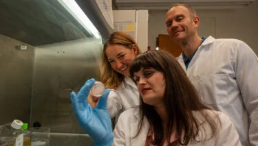 Kristin Bennett holds up a tissue sample as other researchers look on.