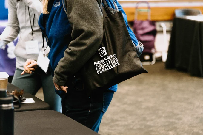 Image of a person carrying a tote bag that says, "Purdue AI in P-12 Education Conference."