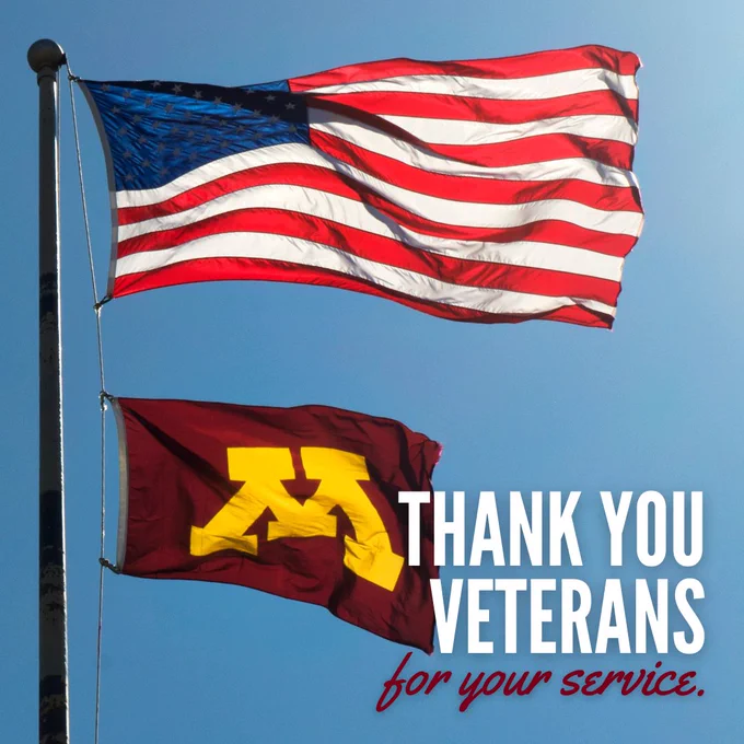 The American flag hangs above the U of M flag with text that reads Thank you Veterans for your service!