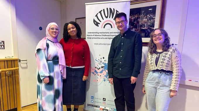 Four young participants standing by the Attune Project's banner